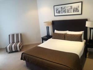 赫维湾阿莱格拉赫维湾美爵公寓式酒店 的一间卧室配有一张大床和一把椅子