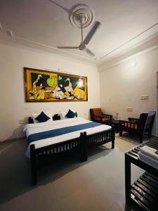 萨瓦伊马多普尔The Ranthambhore Heritage的卧室配有一张床,墙上挂有绘画作品