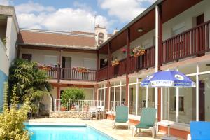 兰斯Logis Hotel au tambour的酒店设有一个游泳池、遮阳伞和椅子。