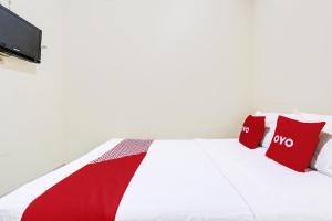 日惹OYO 91803 Gita Graha Guest House Syariah的配有红色枕头的白色床和电视。