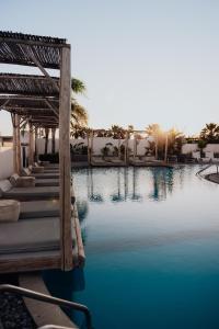 法里拉基Casa Cabana Boutique Hotel & Spa - Adults Only的拥有蓝水和棕榈树的度假村的游泳池