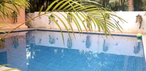 帕拉HERITAGE 7BHK VILLA WITH PRIVATE POOL close to BAGA BEACH的旁边是一座棕榈树的蓝色游泳池