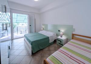 圣贝内代托-德尔特龙托Residence Dolcemare的一间卧室设有两张床和大窗户