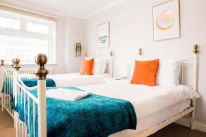 马伯斯Mumbles Apartment near to shops and beach的白色卧室内的两张床,配有橙色枕头