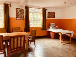 波特尔堡Yes Hostel的一间拥有橙色墙壁和桌椅的用餐室
