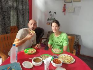 克久拉霍Khajuraho Dreams Homestay的坐在桌子旁吃比萨饼的男人和女人