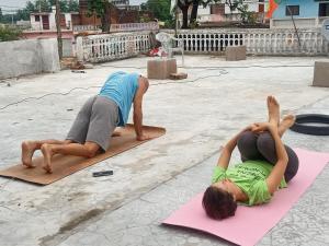 克久拉霍Khajuraho Dreams Homestay的两个人在街上的垫子上做瑜伽