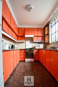 门多萨Panda Hostel Mendoza的橙色的厨房配有橙色橱柜和电器