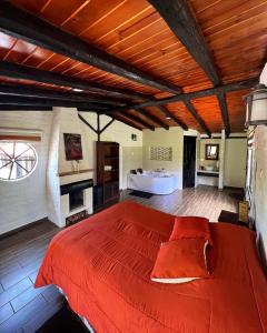 NonoEstancia De La Campiña的一间卧室设有一张红色大床和一个浴缸。