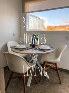 埃尔泰勒罗Blanco Homes & Living 3A的一张带椅子的餐桌和一个读空房子的标牌