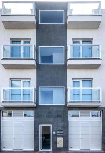 埃尔泰勒罗Blanco Homes & Living 3A的公寓大楼设有白色车库门和窗户。