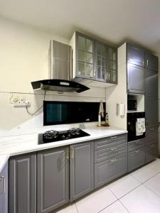 汝来Lapan Ompek Homestay 3 Bedrooms的厨房配有灰色橱柜和炉灶烤箱