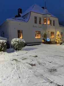 罗威萨Vanha Kanttorila的雪中有一棵圣诞树的白色房子