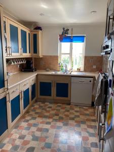 IfordPrivate room in family home的厨房配有蓝色橱柜,铺有瓷砖地板。