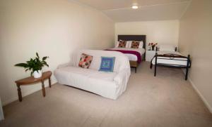 OwakaSurat Bay Lodge by the Sea/Backpackers Hostel的卧室配有白色的沙发和1张床