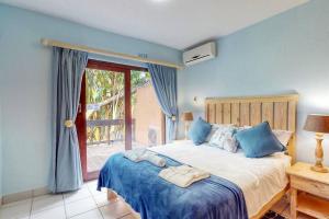 绍斯布鲁姆San Lameer 2107 by Top Destinations Rentals的一间卧室配有一张蓝色墙壁的床和一扇窗户