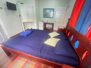 Buccoo米勒旅馆的一间卧室配有一张带紫色床单和枕头的床。