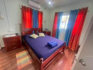 Buccoo米勒旅馆的一间卧室配有红色和蓝色窗帘的床