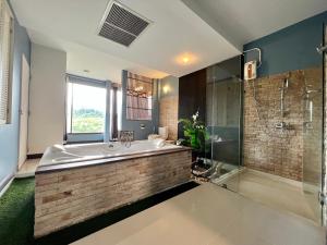 Ban Khanong Phra Taiโรงแรมวิลลา พาราดี的一间带大浴缸和玻璃淋浴的浴室