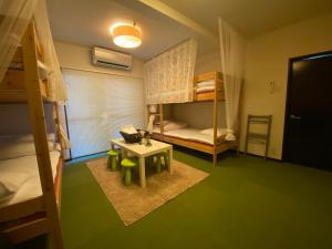 直岛町Bamboo Village Guest House的小房间设有双层床和桌子