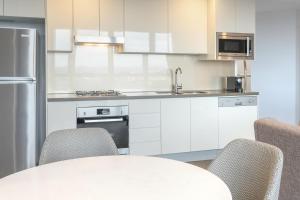 布里斯班Meriton Suites Adelaide Street, Brisbane的厨房配有白色橱柜和桌椅