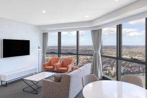 布里斯班Meriton Suites Adelaide Street, Brisbane的客厅配有椅子、电视和窗户。