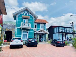 三岛县Nhà Trên Mây - Homstay Tam Đảo的一座蓝色的房子,前面有汽车停放