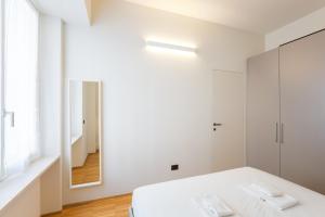 米兰Easylife - Moderno bilocale in zona Porta Romana的白色卧室配有床和镜子