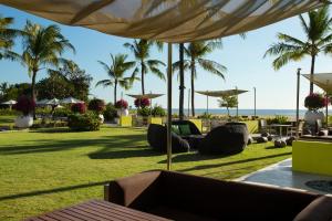 库塔巴鲁纳智选假日酒店的棕榈树度假村和配有椅子及遮阳伞的草坪