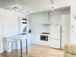 阿德莱德大西洋西海滩公寓的白色的厨房配有桌子和冰箱