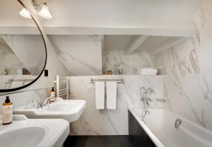 巴黎圣母海岸酒店的浴室设有2个水槽、浴缸和镜子
