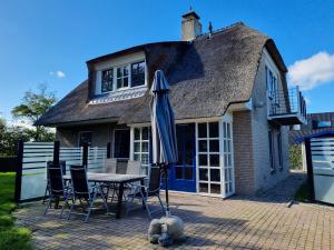 栋堡Prachtig vakantiehuis in Domburg DO38的房屋前的桌椅和遮阳伞