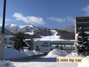 富良野Furano Yayoi-house　的一座白雪覆盖的山,有一座建筑和一个滑雪场