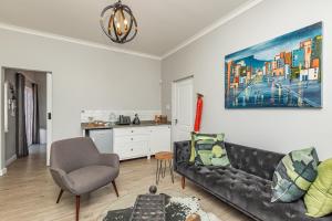 开普敦Spacious Guest Apartment in Rondebosch的一间带黑色沙发的客厅和一间厨房