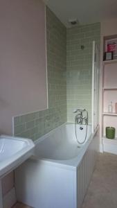 帕兹托Grocer John's. The heart of the old town的浴室铺有绿色瓷砖,配有浴缸。