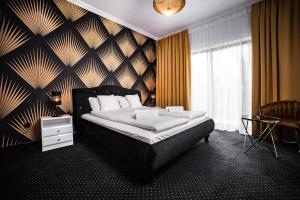 斯塔加德什切青POŁUDNIK PARK Boutique Hotel Conference&SPA的一间卧室设有一张大床,拥有黑色和金色的墙壁