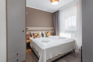 米兹多洛杰Miedzyzdroje SEASIDE Apartments Bel Mare by Renters的一间卧室配有一张带白色床单的床和一扇窗户。