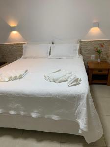 瓜拉米兰加Pousada Chale Cana Brava的一张白色的床,上面有两条白色毛巾
