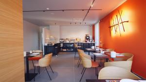西尔米奥奈克里斯托酒店的餐厅拥有橙色的墙壁和桌椅