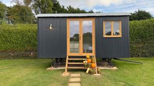 LamberhurstShepherds Hut at Cedar Gables的坐在田野顶上的黑色小房子