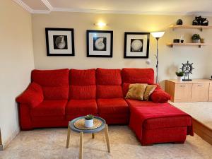 阿里纳加Las Nasas, Acogedor apartamento cerca de la playa的客厅里一张红色的沙发,配有桌子