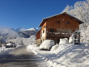 BeauneChambre d'hôtes à la ferme的雪覆盖的房子,里面装有汽车停放在雪地里