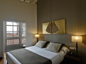 圣地亚哥－德孔波斯特拉Carris Casa de la Troya的一间卧室配有一张带两盏灯的床和一扇窗户。