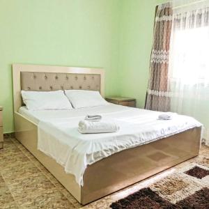 地拉那Relax Hostel的一间卧室配有一张带白色床单的床和一扇窗户。