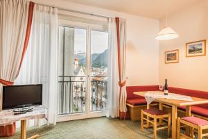 奥蒂塞伊Aquila Dolomites Residence的客厅设有大窗户和一张桌子及电视