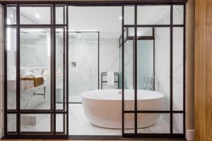 尤西德福拉胜利商务酒店 的浴室配有白色浴缸和玻璃墙