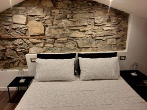 布里维奥Luxury Room La Terrazza sul Lago di Como的一间卧室设有石墙和一张带枕头的床。