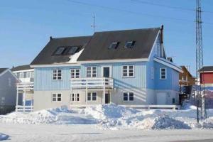 努克Nice and cozy flat的前面有雪的蓝色和白色房子