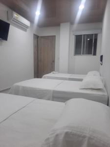SoledadHOTEL MAR DEL CARIBE的白色的客房设有两张床和窗户。
