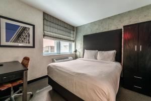 纽约Solita Soho Hotel的一间卧室配有一张大床、一张桌子和一张四柱床。